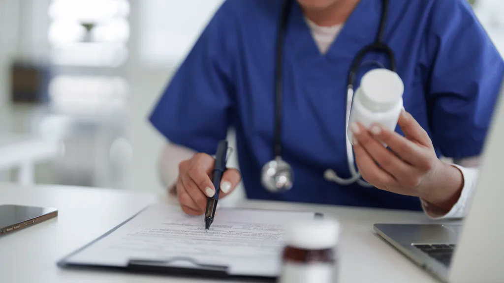 Cartela de comprimidos ao lado de um copo d'água, ilustrando a relação entre medicamentos e bruxismo