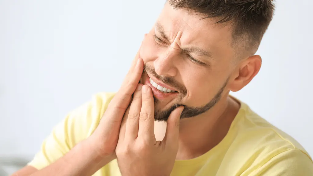 Pessoa com a mão no rosto sentindo dor de dente insuportável